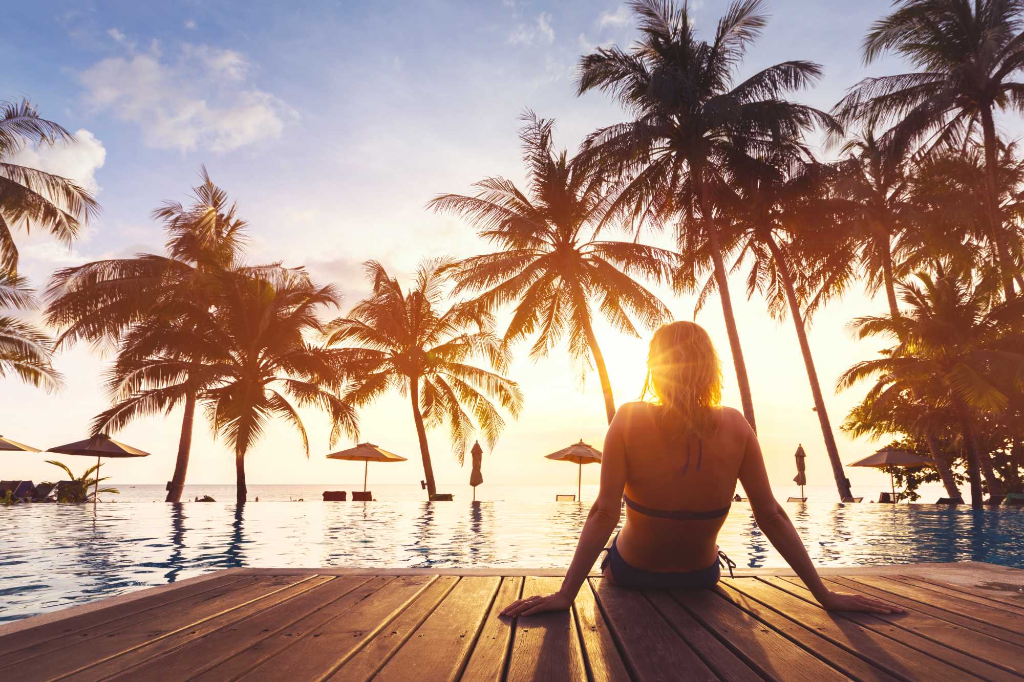 Frau, die Ferien im luxuriösen Hotelresort am Strand mit Pool und tropischer Landschaft in Strandnähe genießt